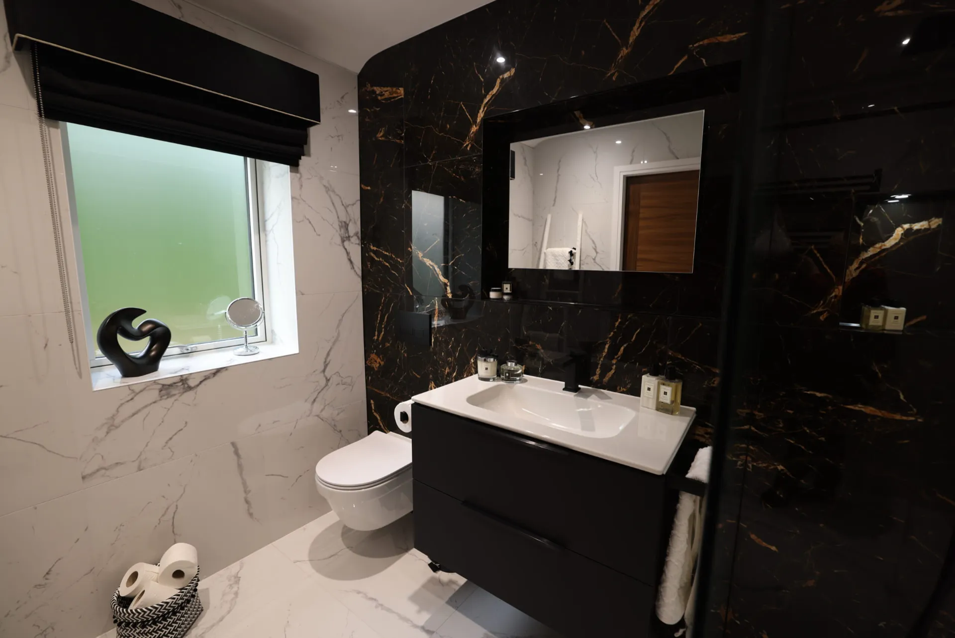 Bathroom with black and gold marble-effect walls, a black vanity unit and a wall-hung WC