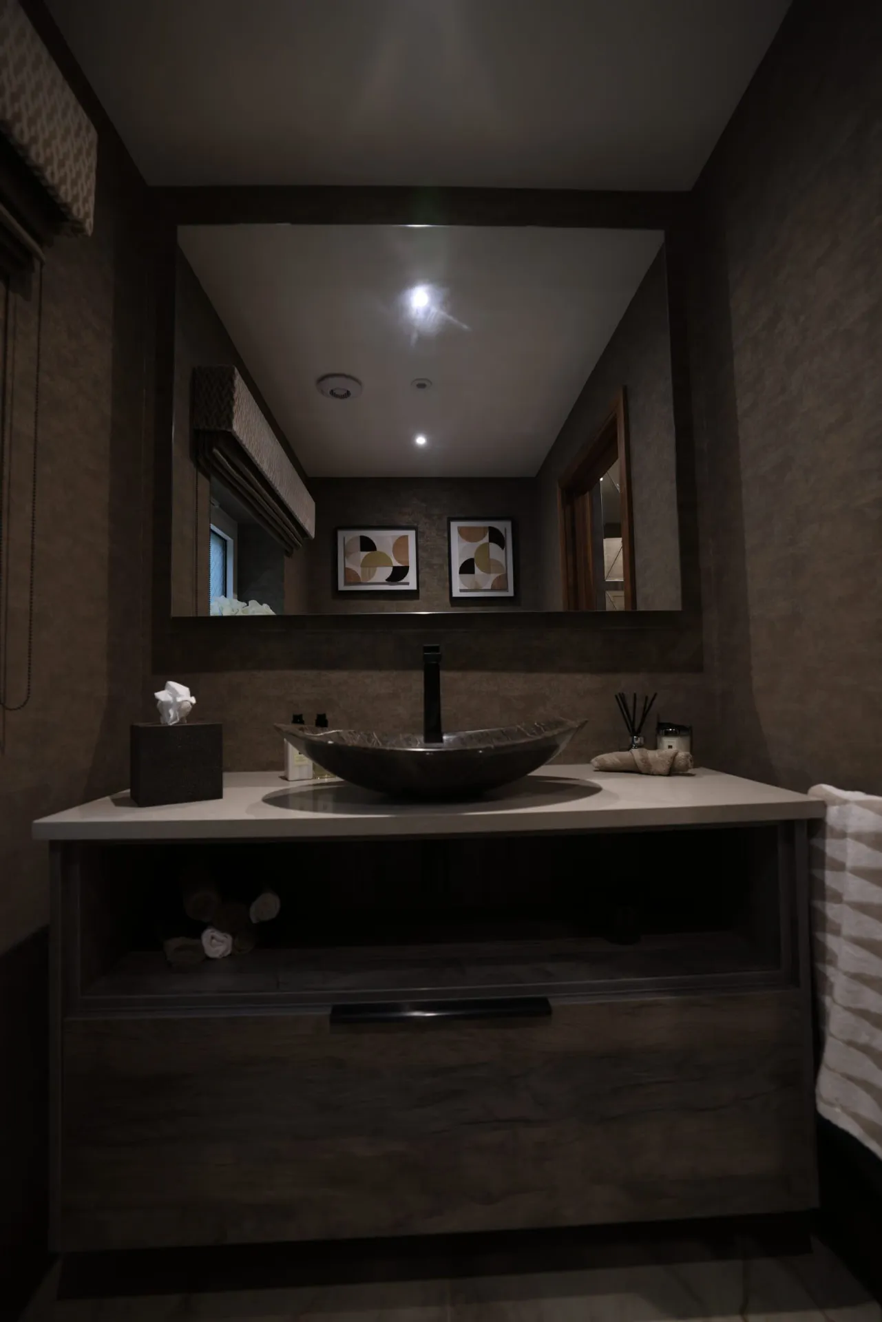 Vessel basin on a fitted vanity with open storage beneath a large wall mirror