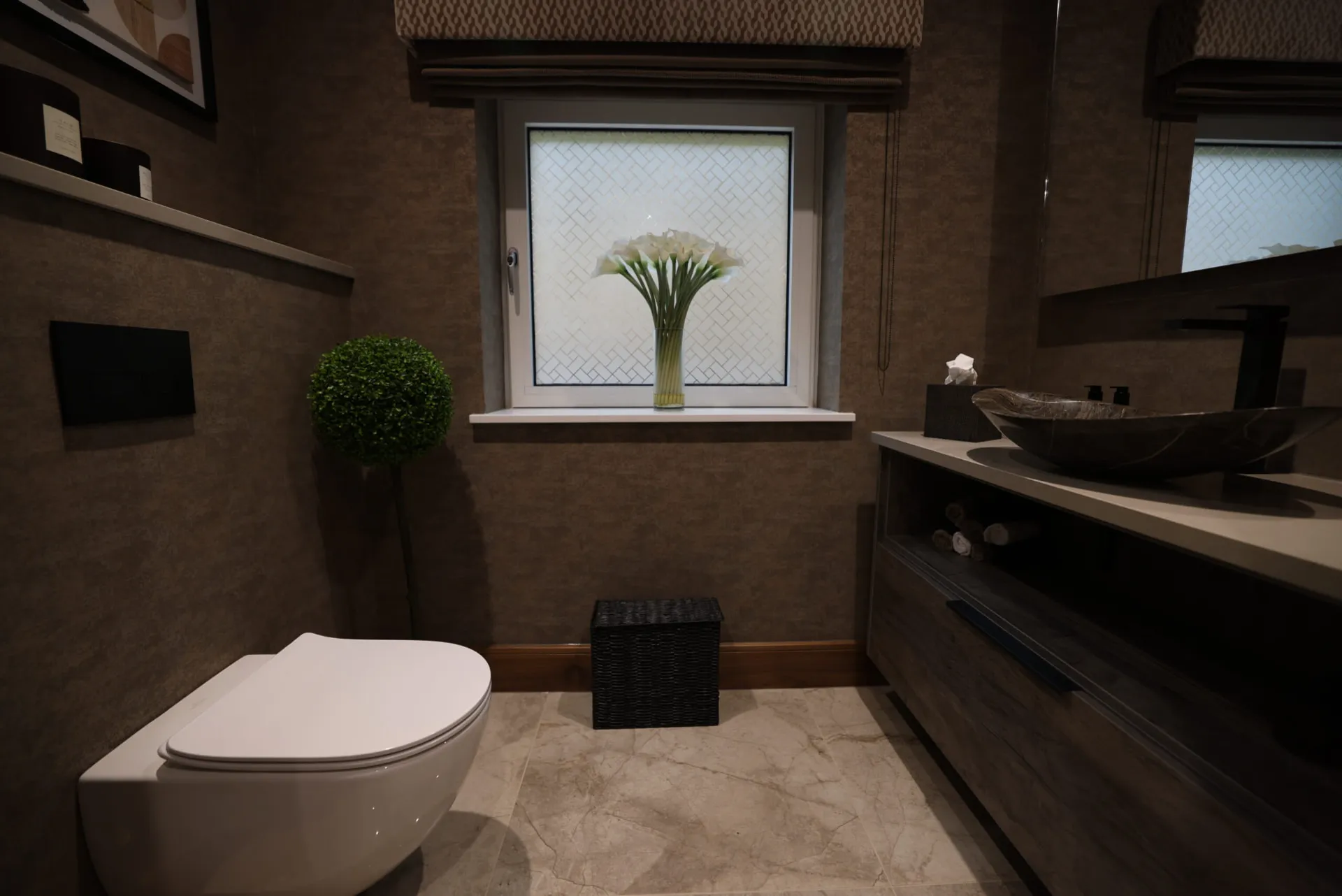 Cloakroom with textured walls, a wall-hung WC and a stone vessel basin on a timber-effect vanity