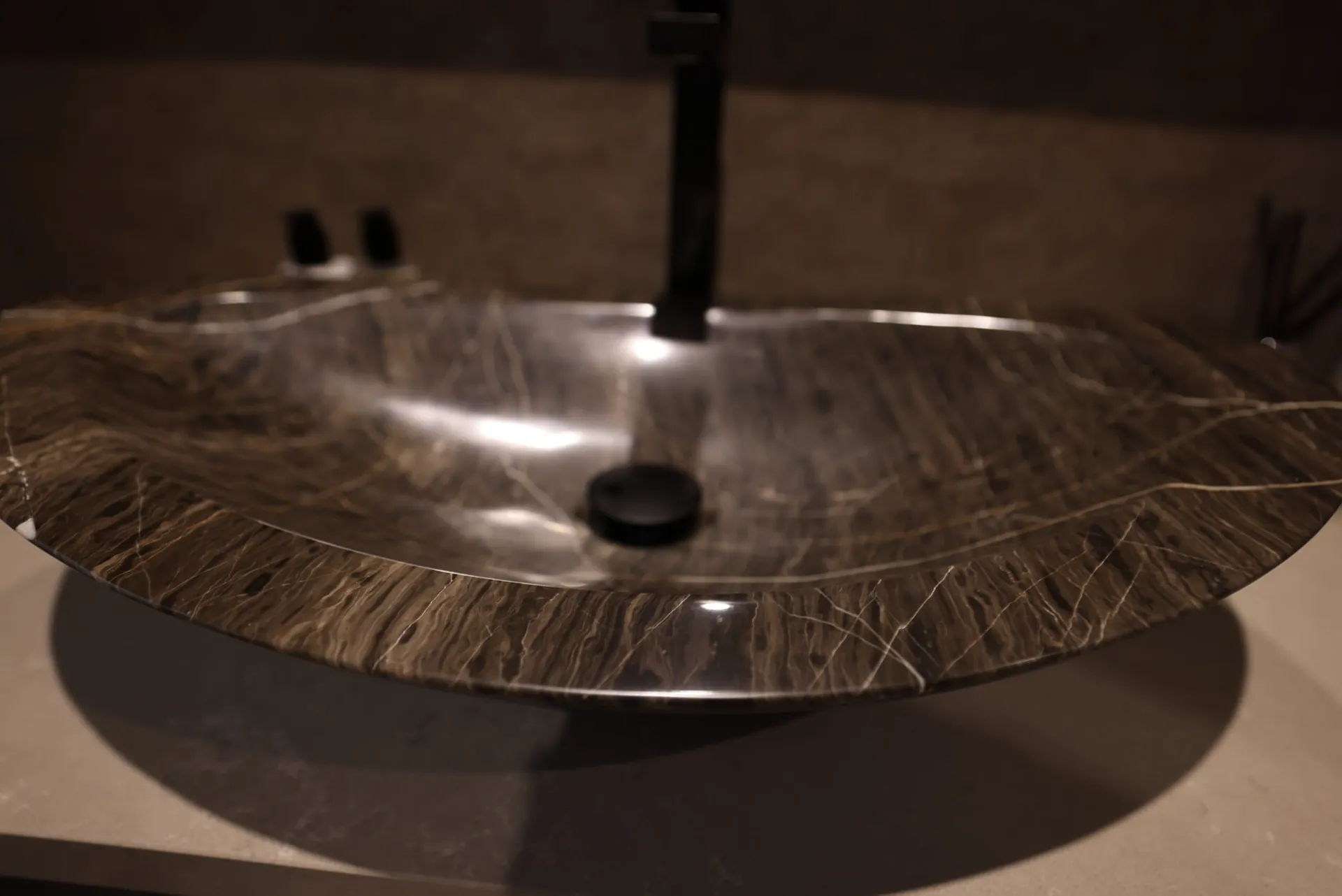 Close detail of a veined stone vessel basin with a black tap